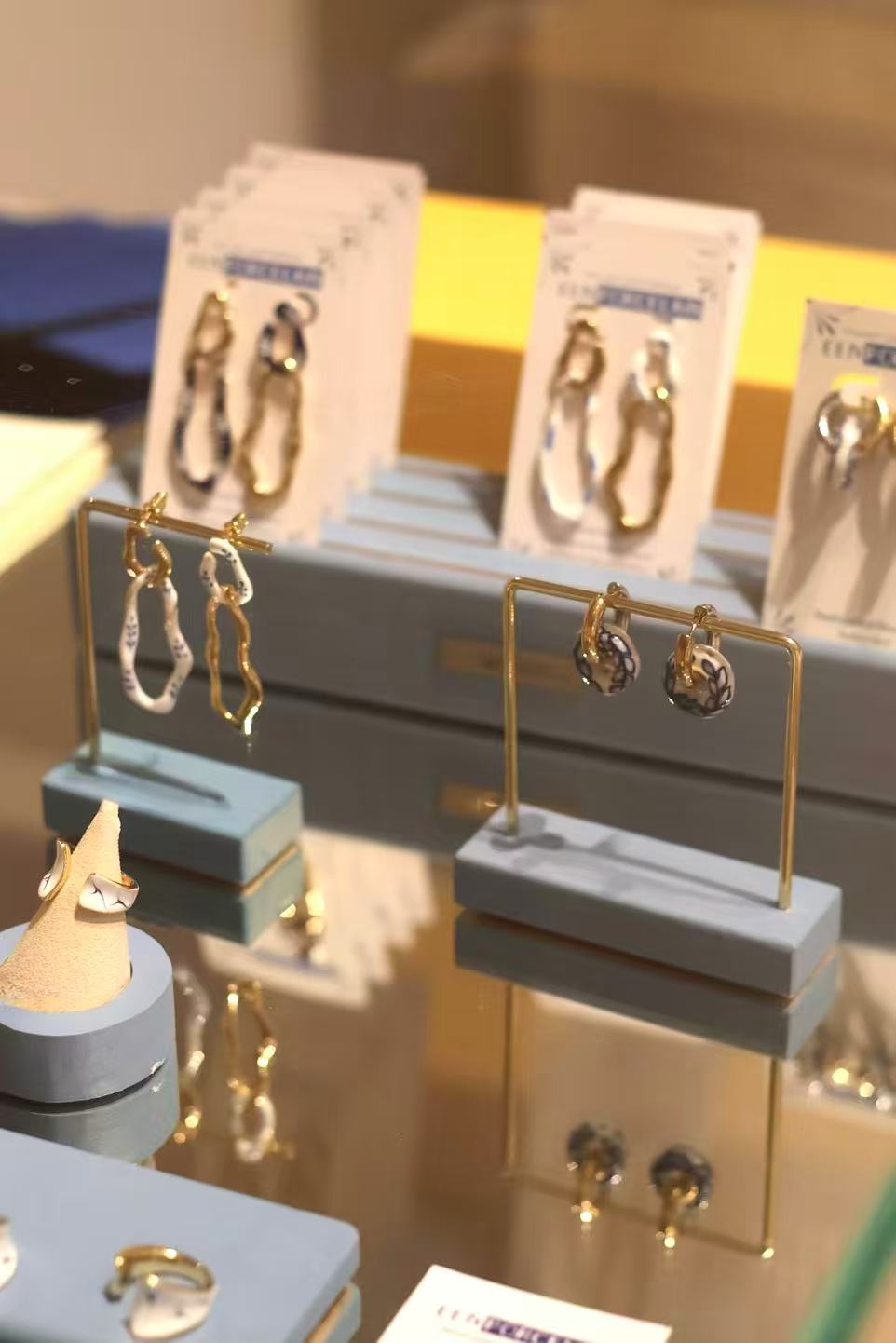 Gold earrings on display stands with branded cards in the background